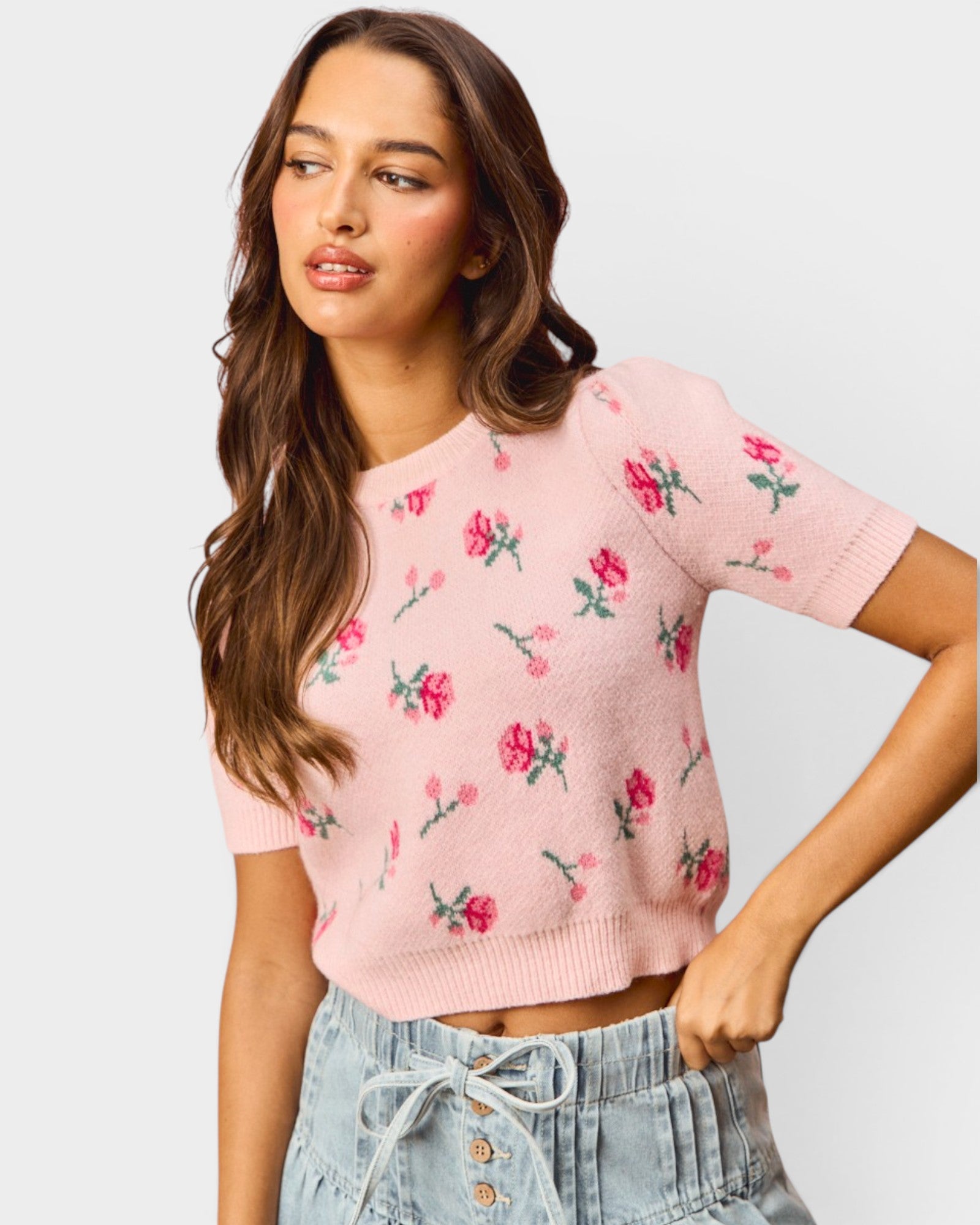 Woman wearing a pink floral sweater against a light gray background