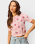 Woman wearing a pink floral sweater against a light gray background