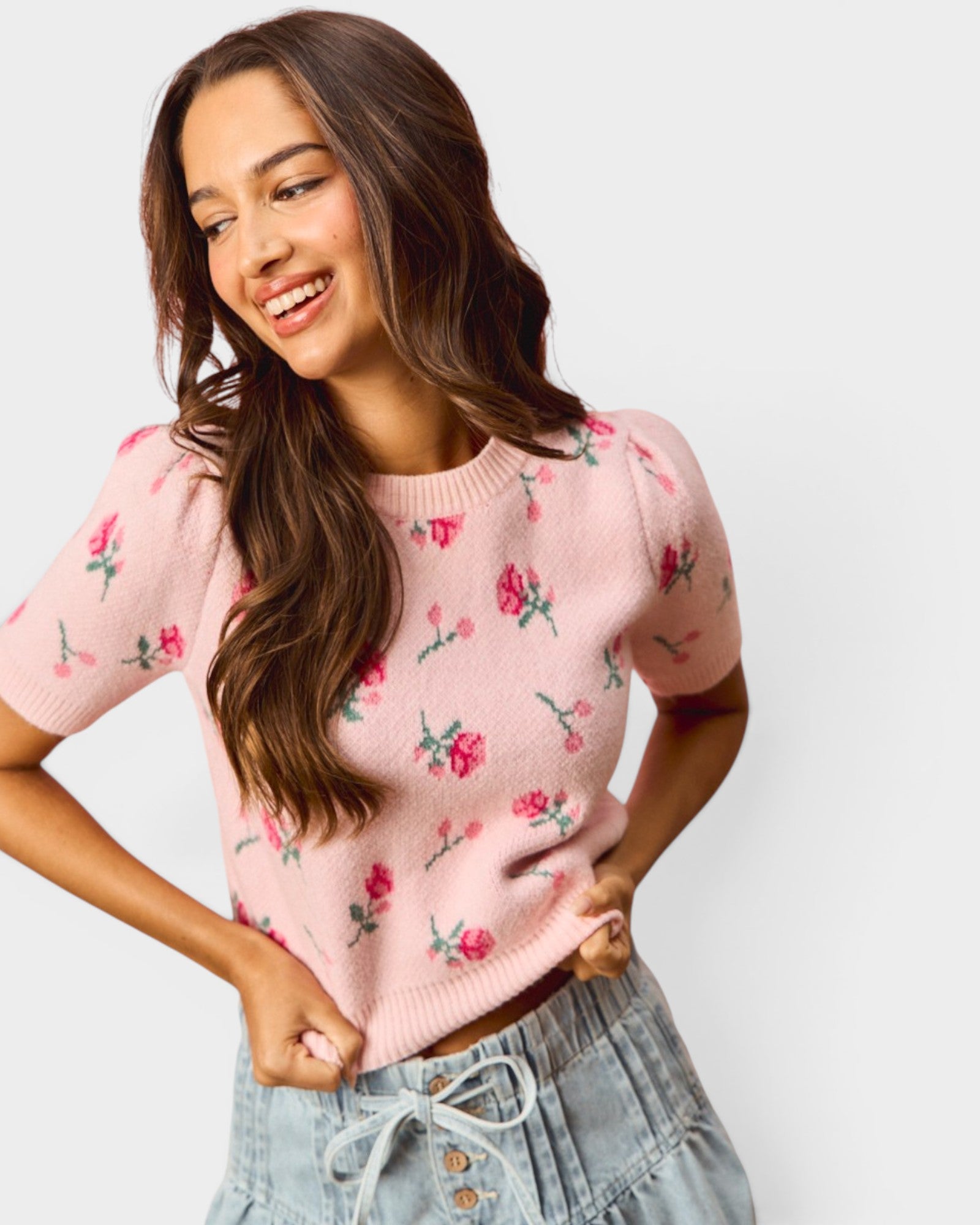 Woman wearing a pink floral sweater against a white background