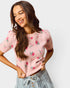 Woman wearing a pink floral sweater against a white background