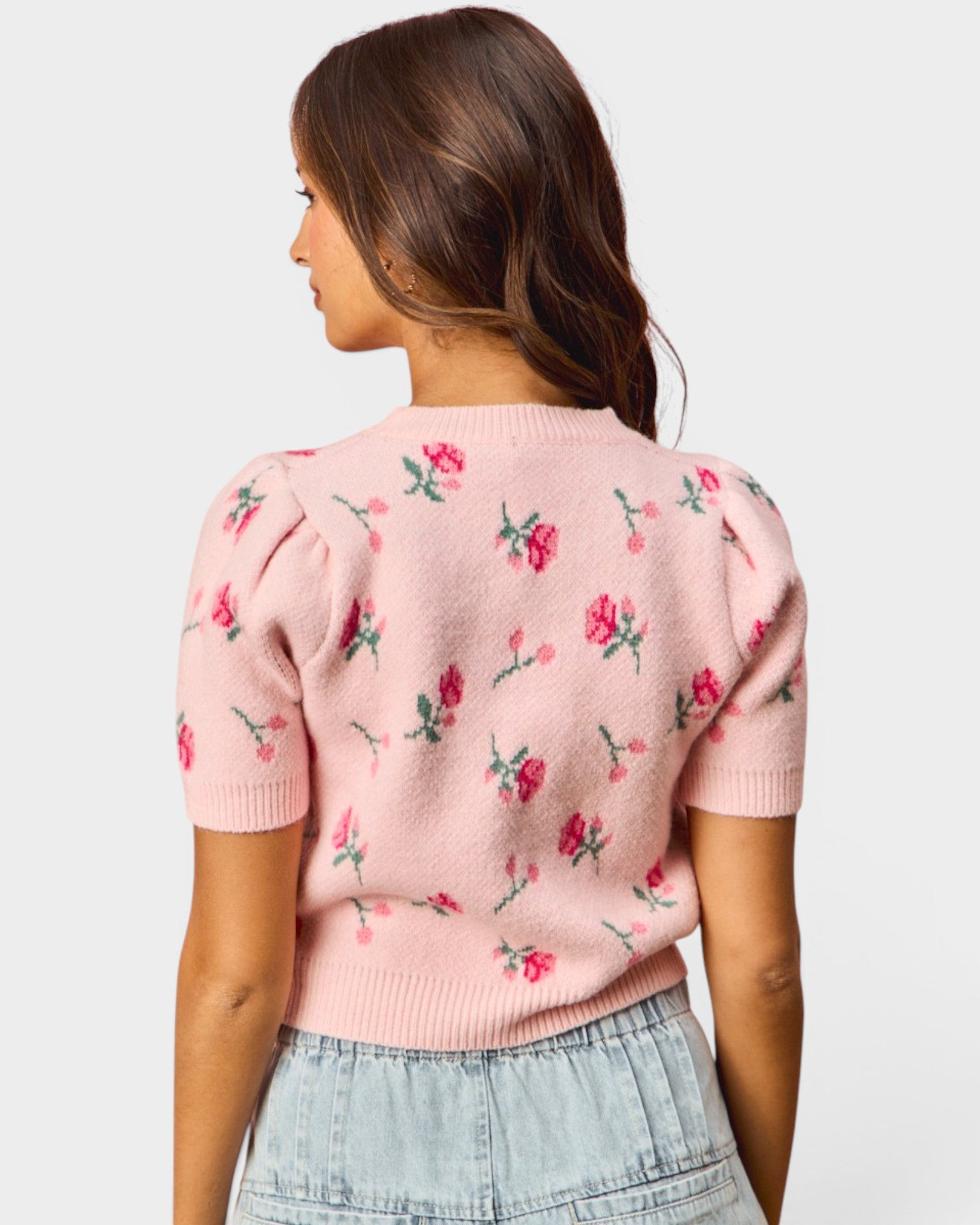 Woman wearing a pink floral-patterned sweater against a white background