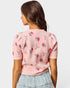 Woman wearing a pink floral-patterned sweater against a white background
