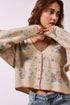 Woman wearing a floral patterned cardigan against a white background