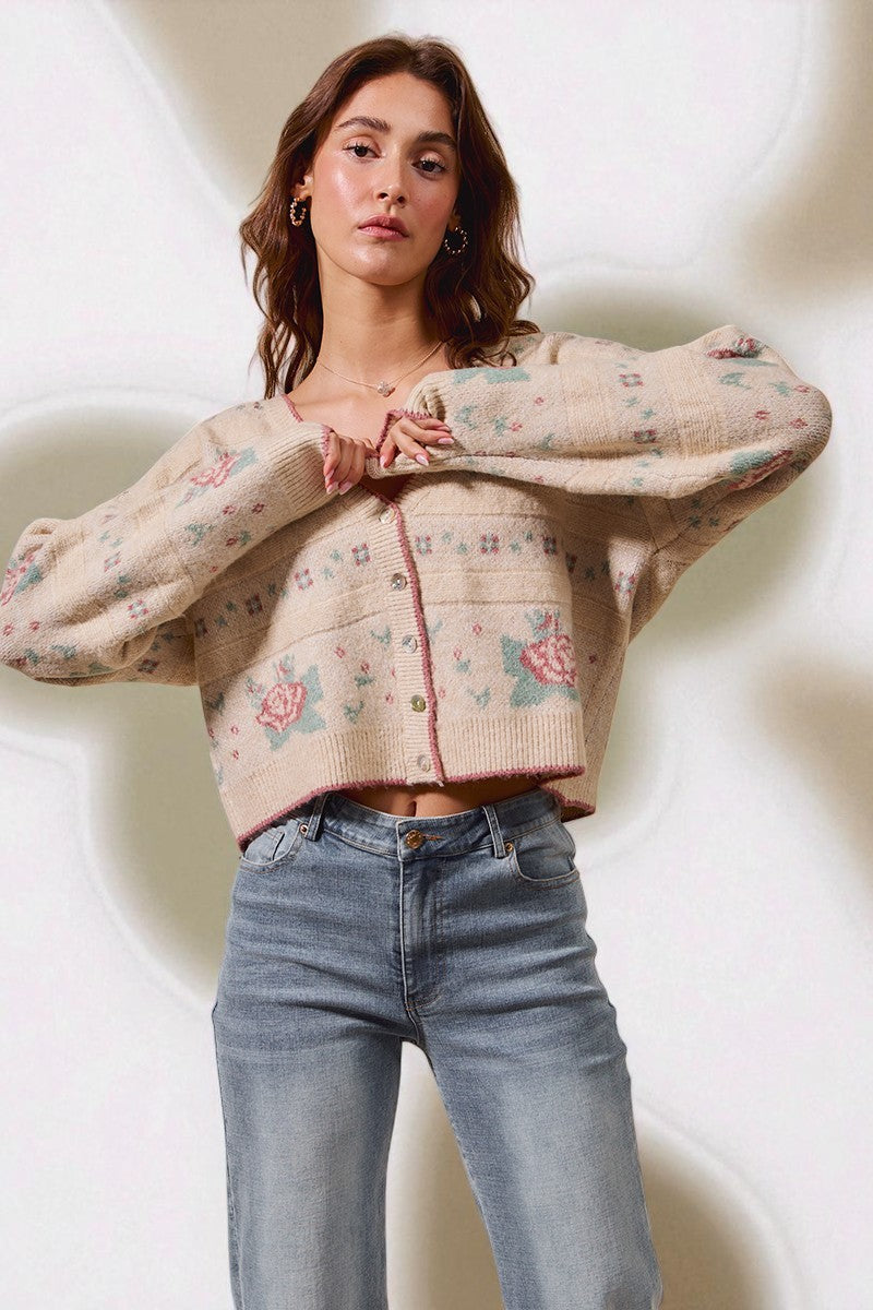 Woman wearing a floral-patterned cardigan and jeans against a plain background