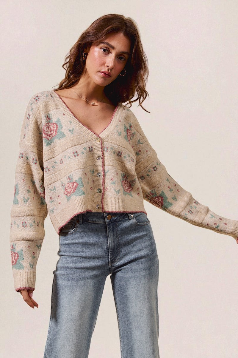 Woman wearing a floral patterned cardigan and jeans on a plain background