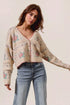 Woman wearing a floral patterned cardigan and jeans on a plain background