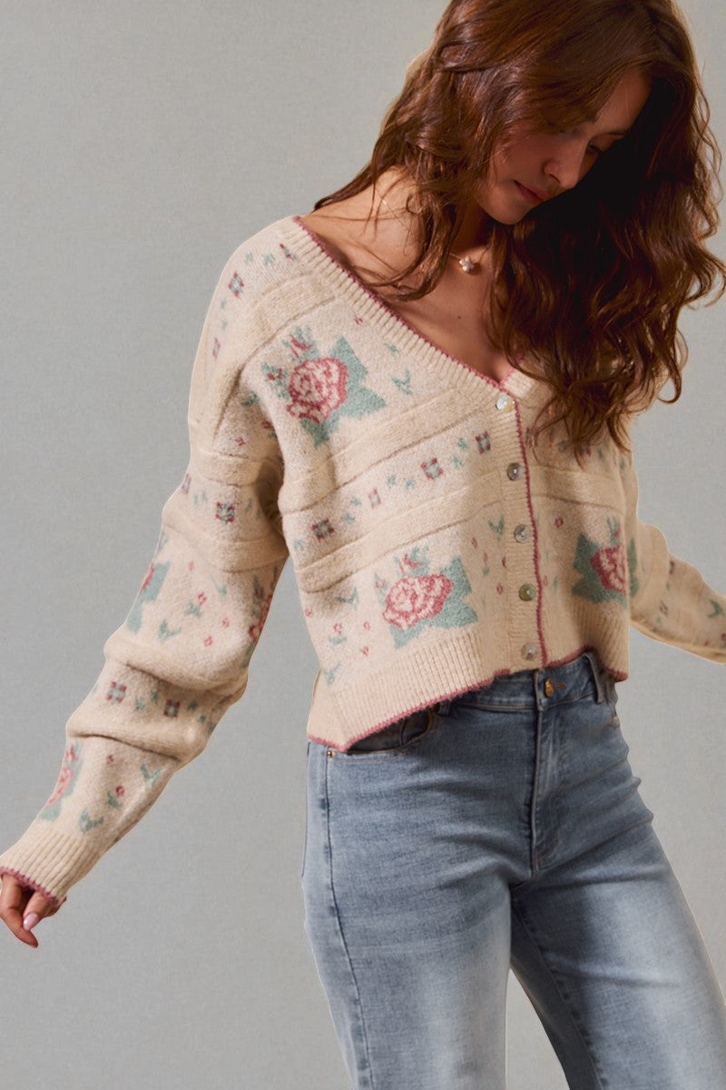 Woman wearing a floral patterned sweater and jeans against a gray background