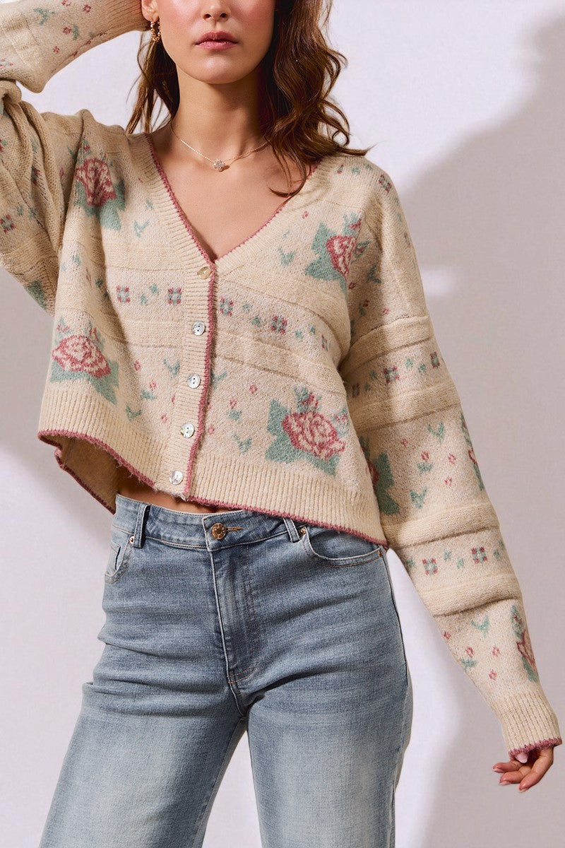 Woman wearing a floral patterned cardigan and jeans on a plain background