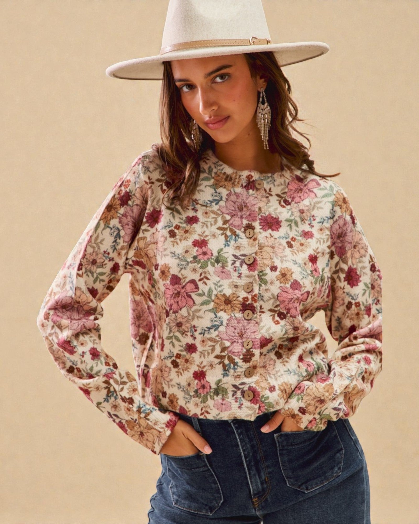 Woman wearing a floral blouse and wide-brimmed hat against a beige background