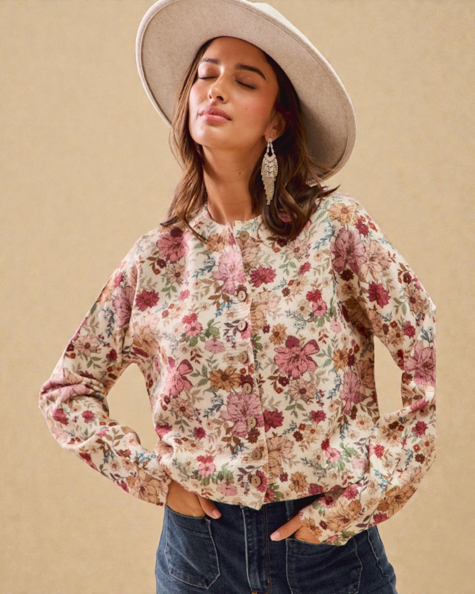 Woman wearing a floral blouse and wide-brimmed hat against a beige background