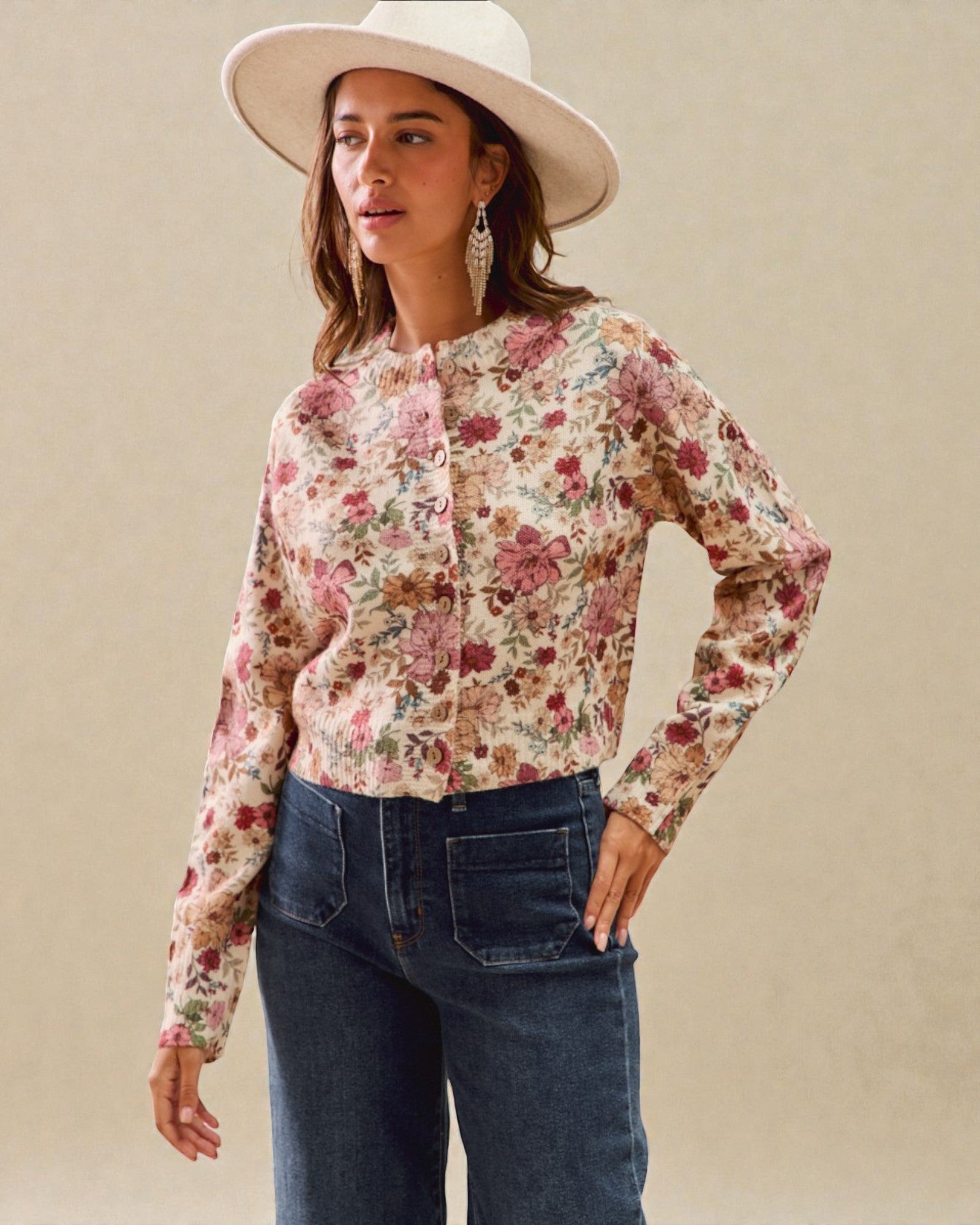 Woman wearing a floral blouse and wide-brimmed hat against a beige background