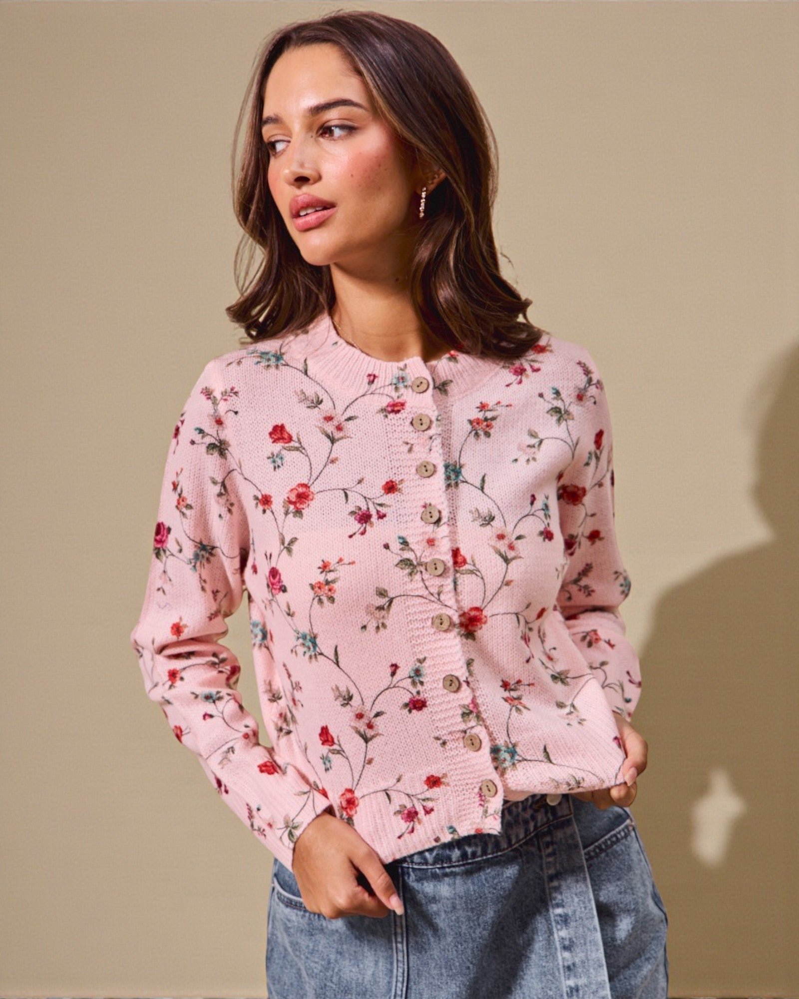Woman wearing a pink floral cardigan against a beige background