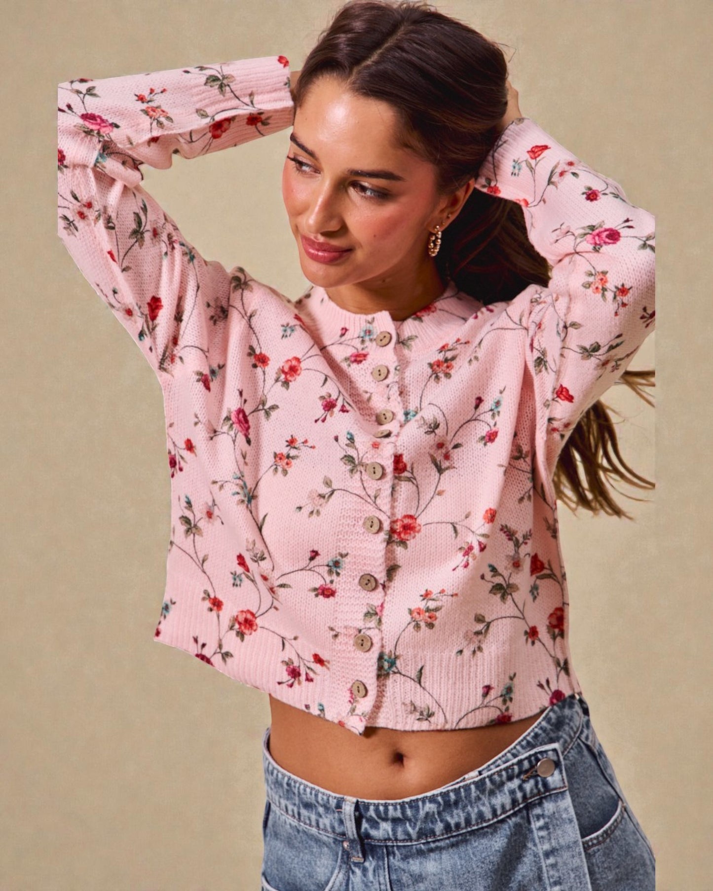 Woman wearing a pink floral blouse and blue jeans against a beige background