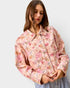 Woman wearing a floral patterned jacket on a plain background
