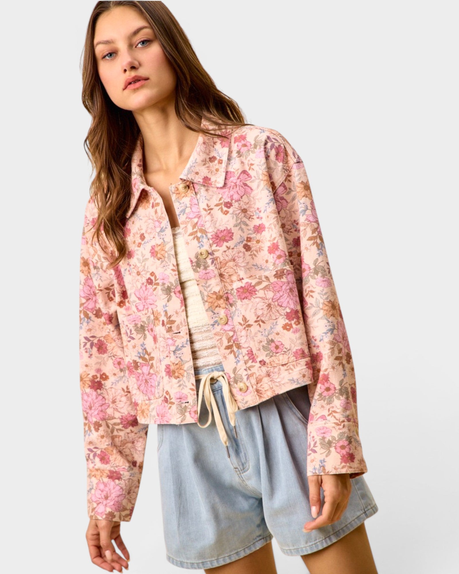 Woman wearing a floral shirt and denim shorts on a plain background