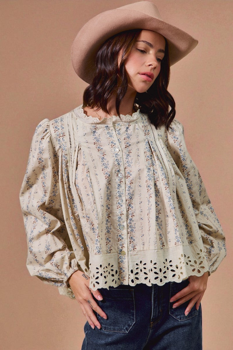 Woman wearing a floral blouse and wide-brimmed hat against a beige background