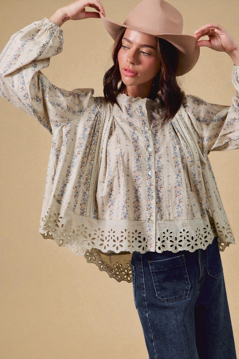 Woman wearing a floral blouse with lace details and a beige hat against a beige background