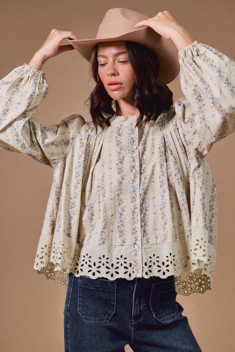Woman wearing a floral blouse and wide-brimmed hat against a brown background