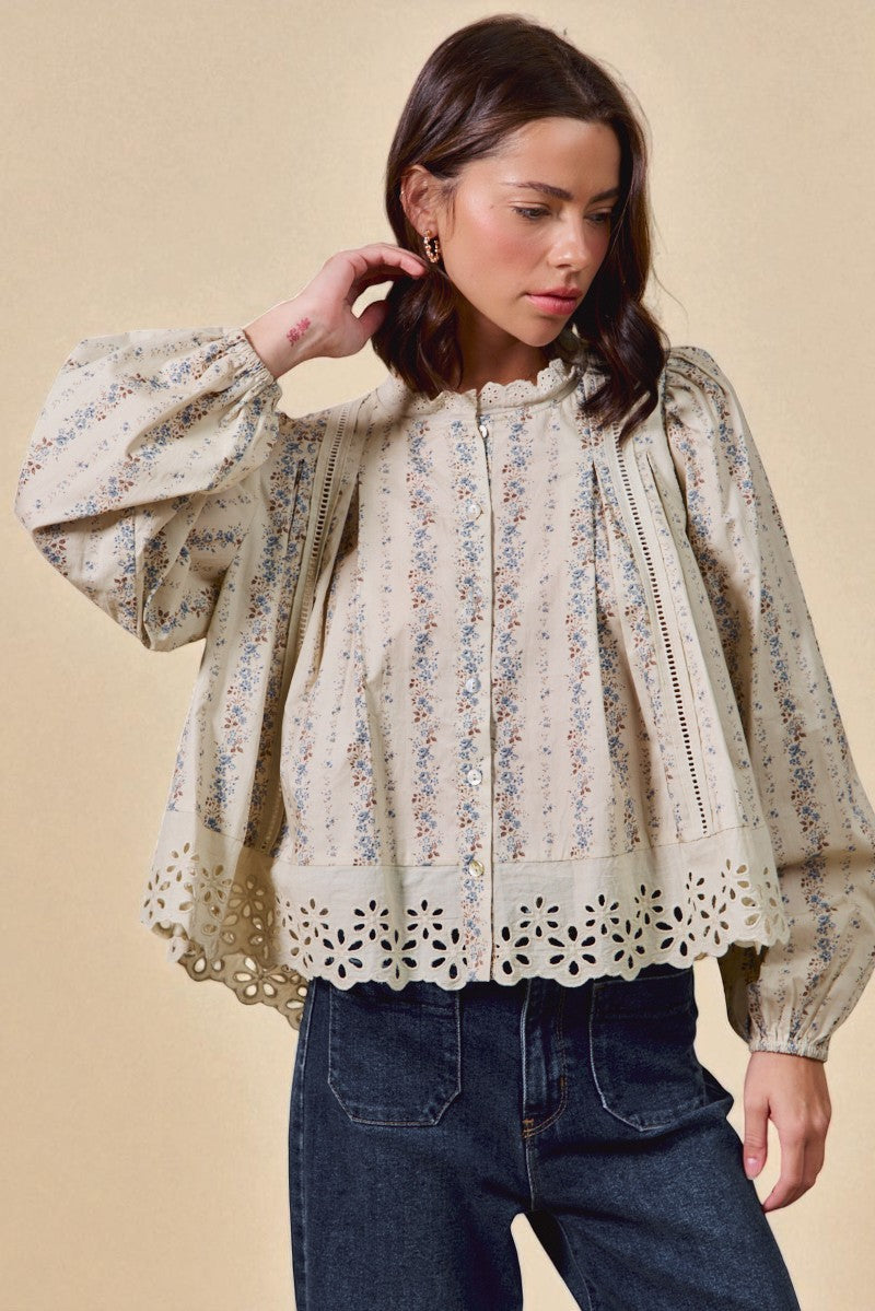 Woman wearing a floral blouse with long sleeves against a beige background