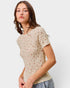 Woman wearing a beige floral-patterned t-shirt against a plain background