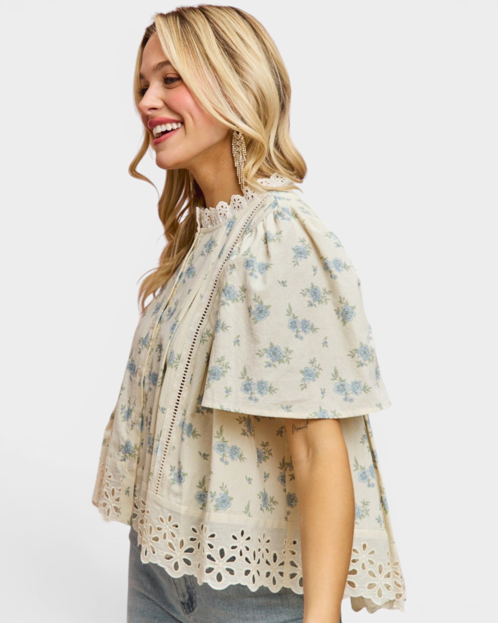 Woman wearing a floral blouse with lace details on a white background