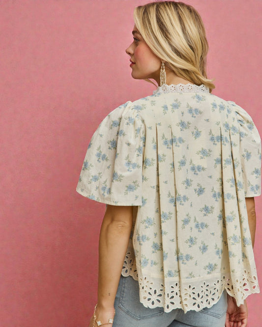 Woman wearing a floral blouse with lace trim against a pink background