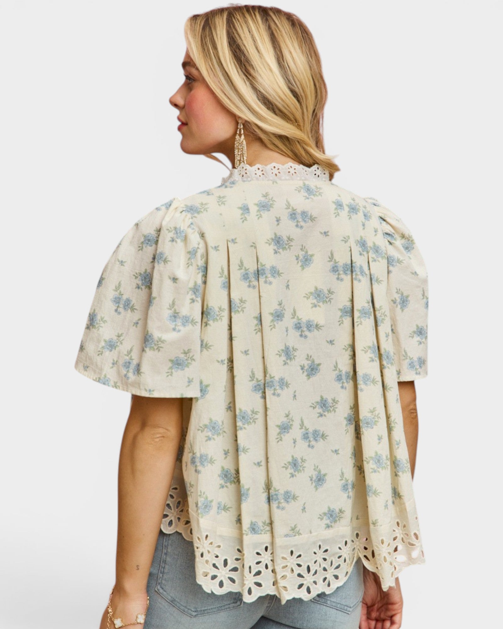 Woman wearing a floral blouse with lace details on a white background
