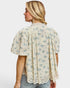 Woman wearing a floral blouse with lace details on a white background