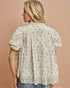 Woman wearing a floral blouse against a beige background