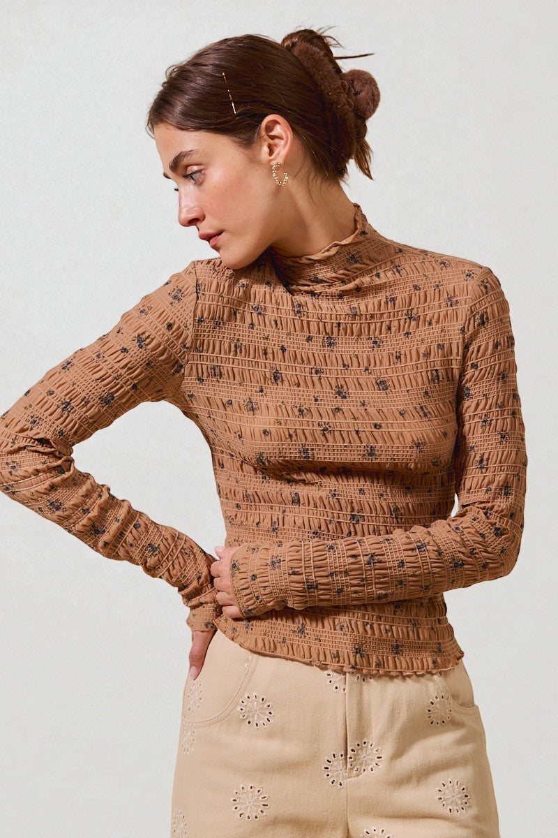 Woman wearing a brown patterned sweater against a plain background