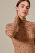 Woman wearing a brown patterned sweater against a beige background