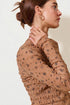Woman wearing a brown patterned dress with a plain background