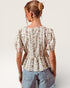 Woman wearing a floral blouse and denim shorts on a plain background