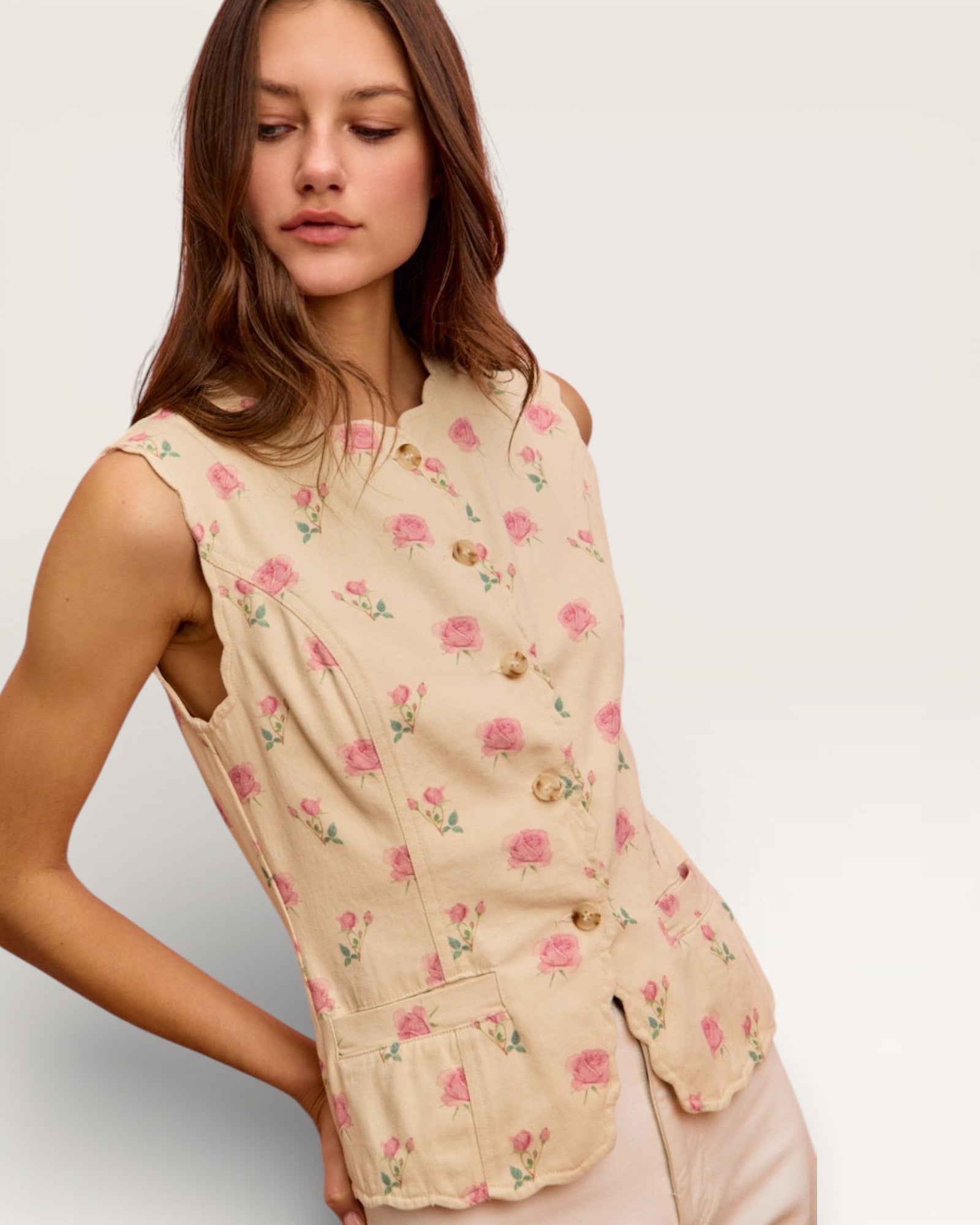 Woman wearing a beige floral sleeveless top against a plain background