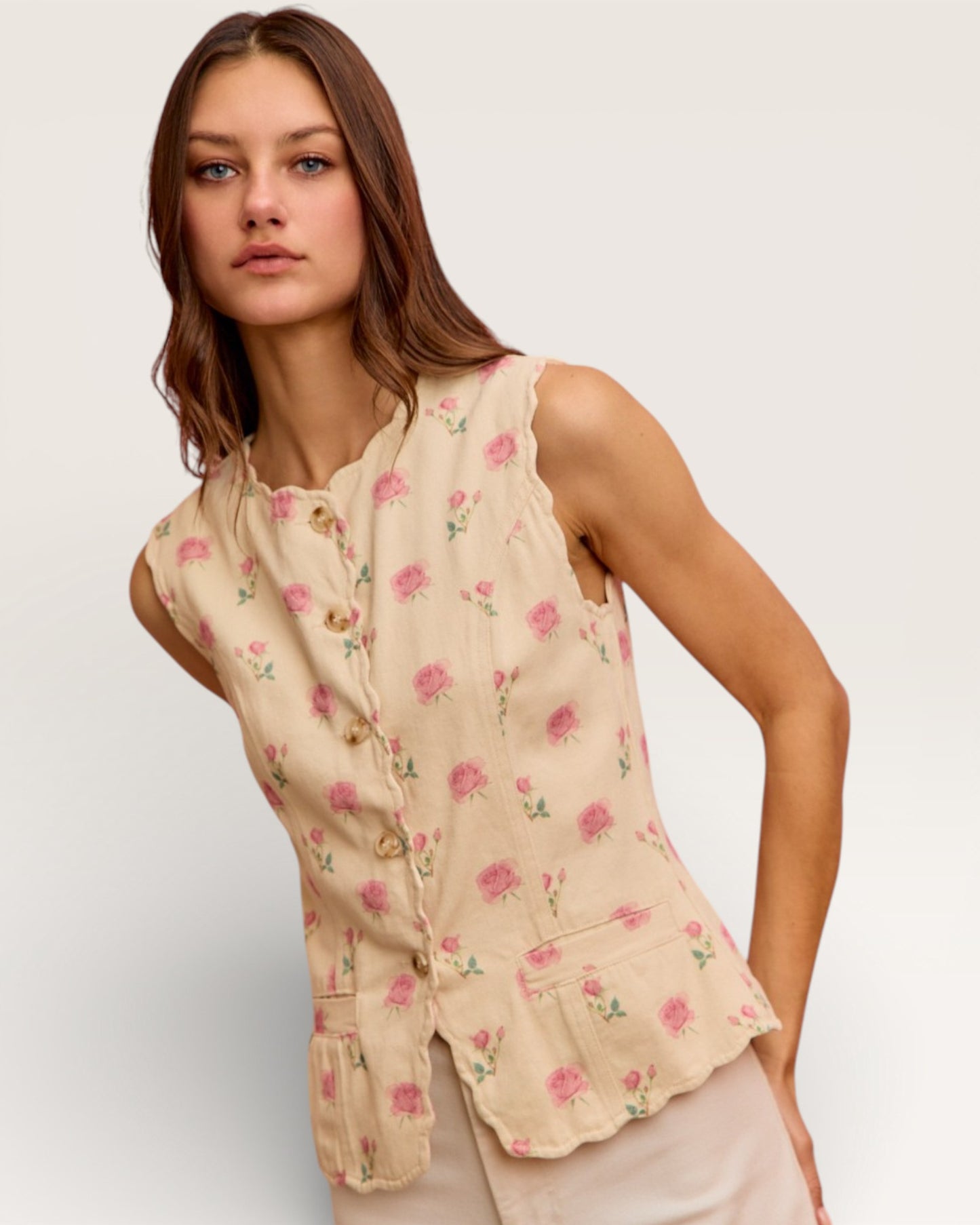 Woman wearing a beige sleeveless top with floral pattern on a plain background