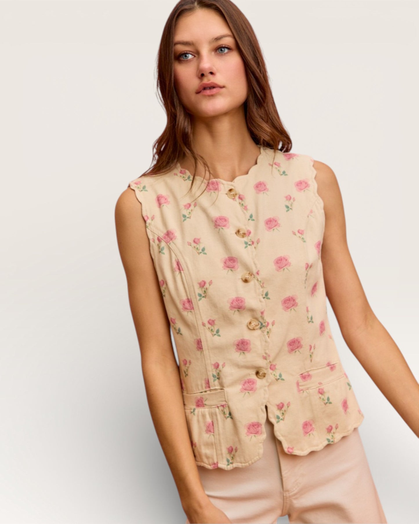 Woman wearing a sleeveless floral top against a plain background