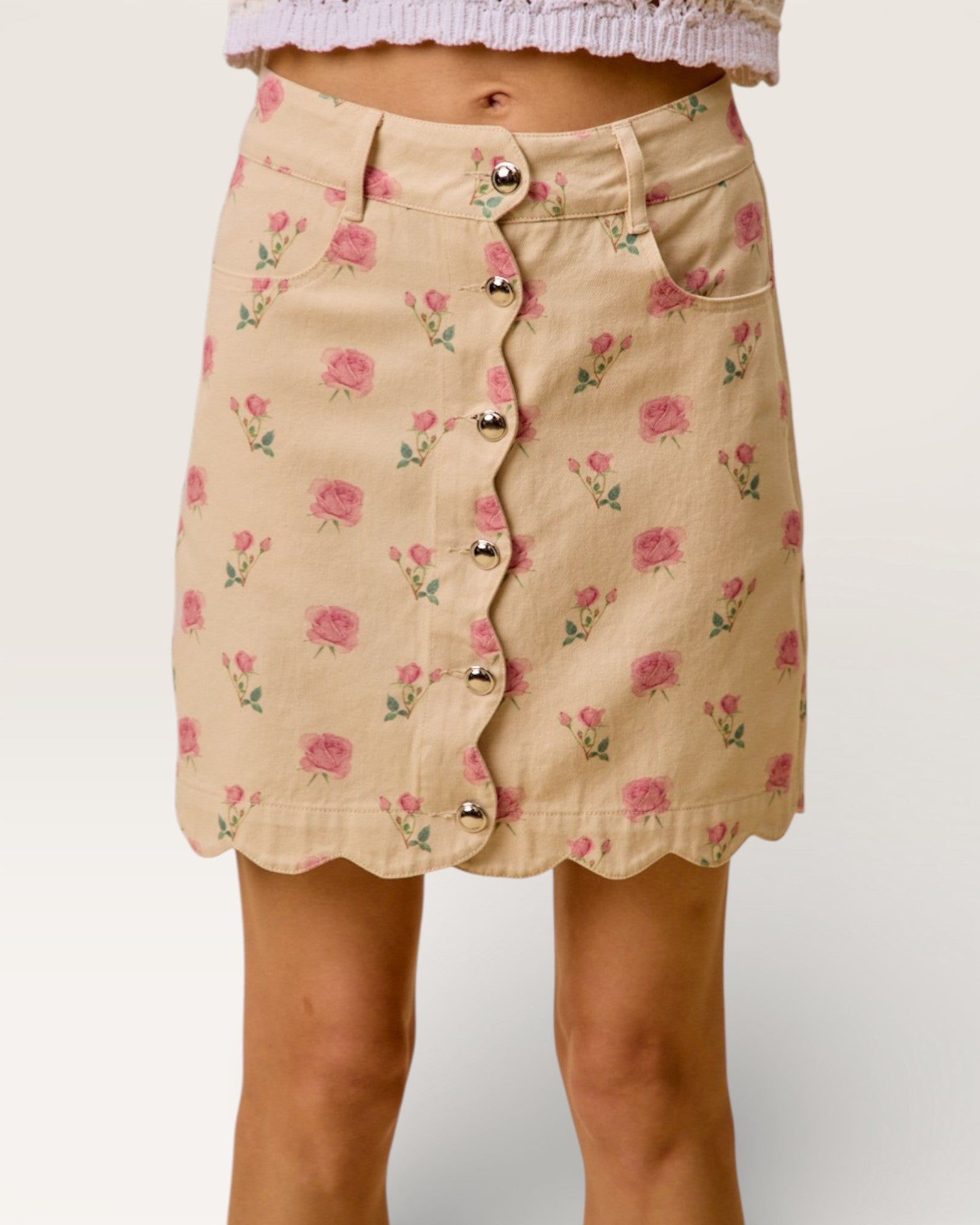 Beige skirt with pink floral pattern and silver buttons on a plain background