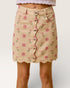 Beige skirt with pink floral pattern and silver buttons on a plain background