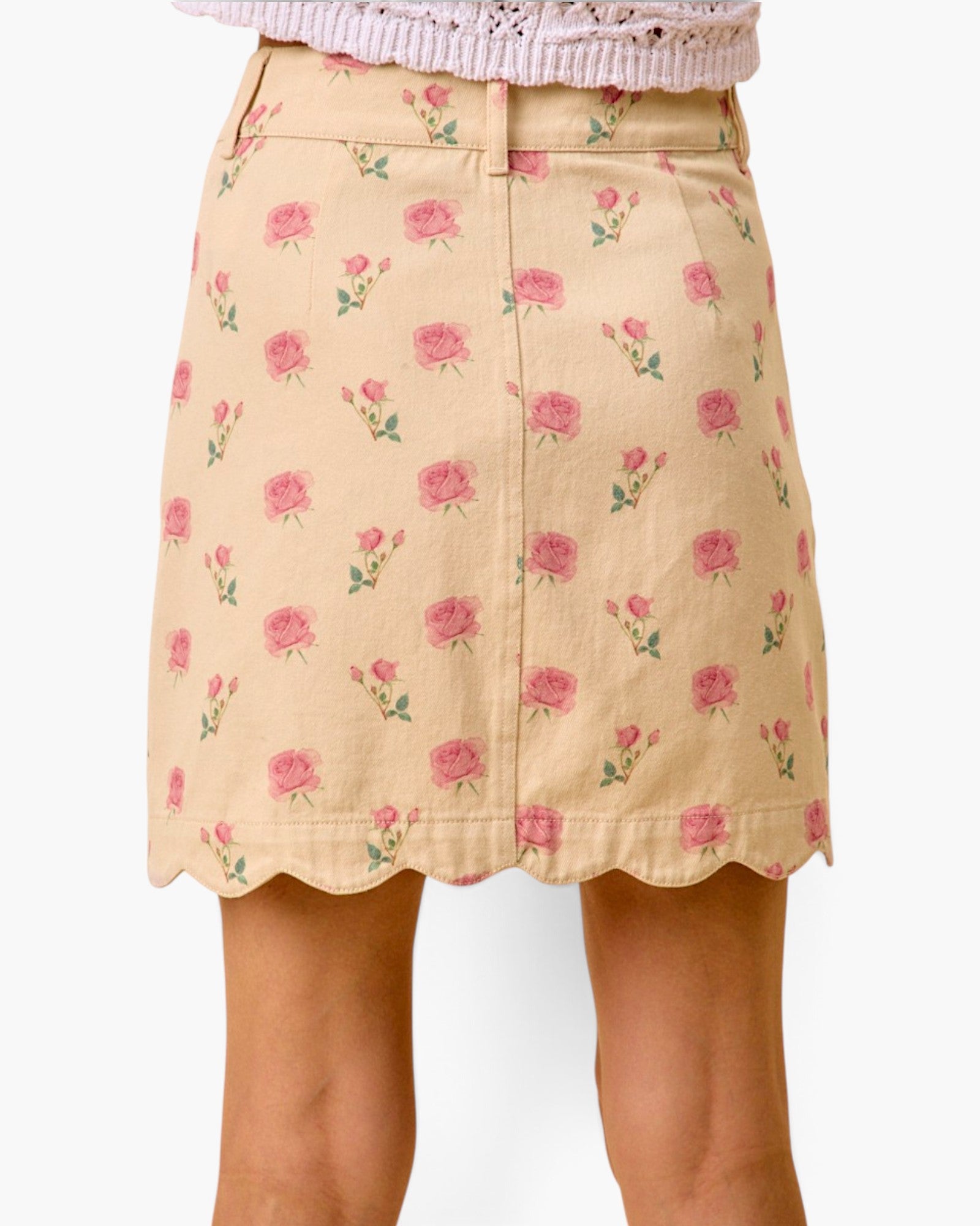 A beige A-line skirt with a pink rose floral print and scalloped hem, shown on a model against a white background.