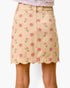 A beige A-line skirt with a pink rose floral print and scalloped hem, shown on a model against a white background.