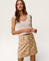 Woman wearing a white lace top and floral skirt on a plain background