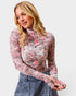 Woman wearing a floral long-sleeve top against a plain background