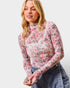 Woman wearing a floral long-sleeve top against a white background