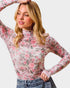 Woman wearing a floral long-sleeve top with a plain background