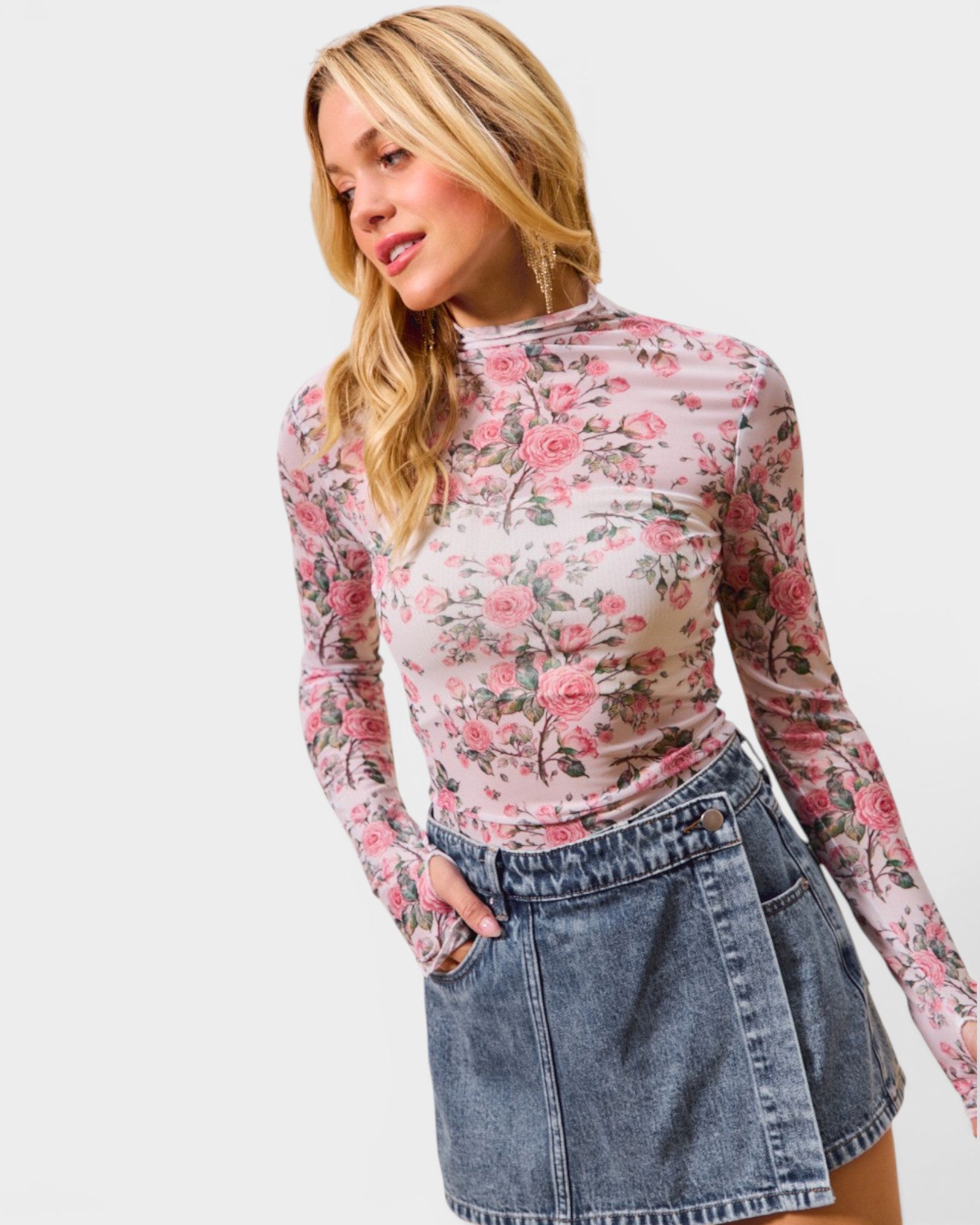 Woman wearing a floral long-sleeve top and denim skirt on a white background