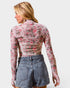 Woman wearing a floral long-sleeve top and denim shorts on a white background