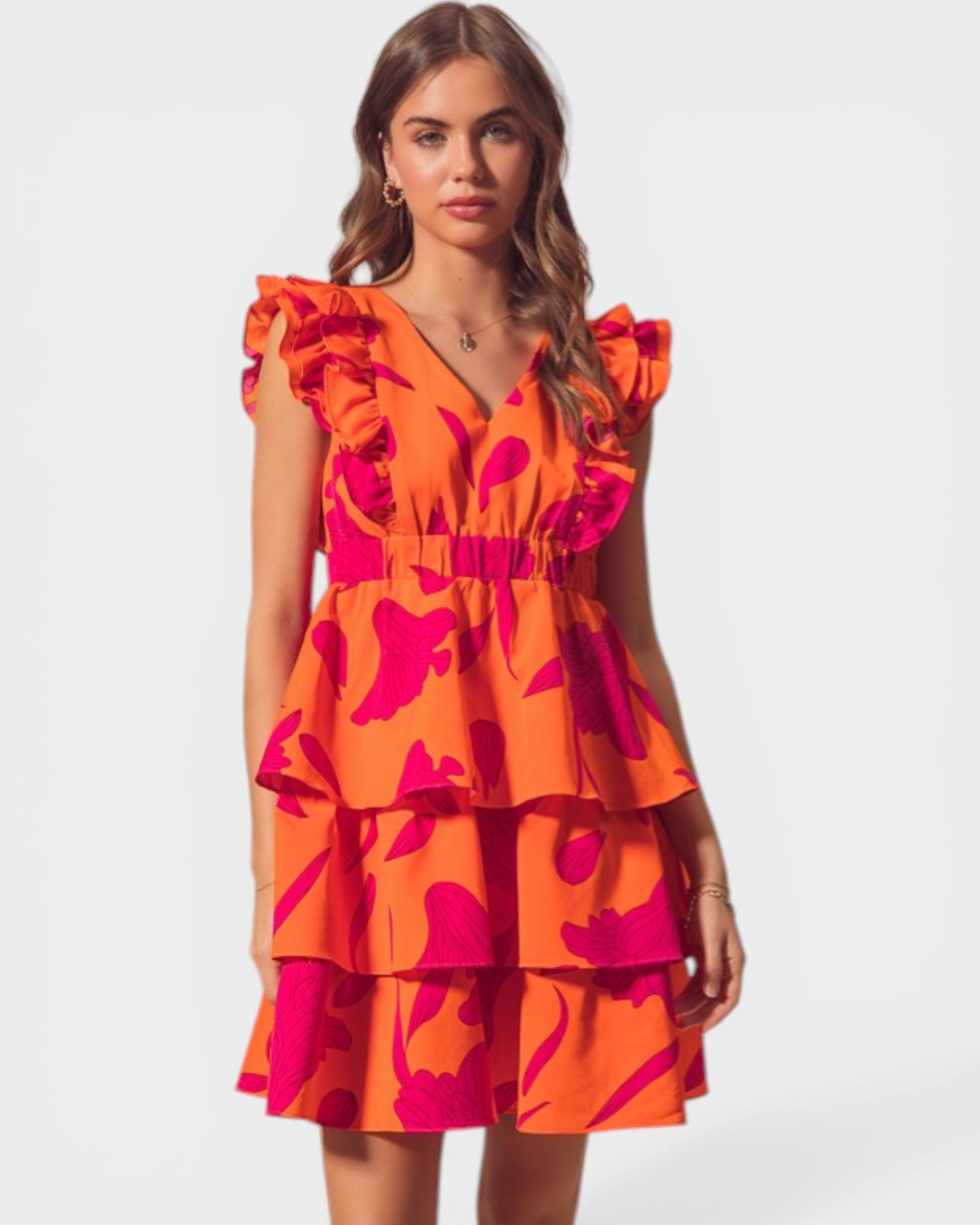 Woman wearing an orange and pink dress with ruffled sleeves on a white background