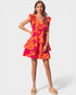 Woman wearing a bright orange and pink dress on a white background