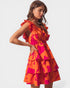 Woman wearing an orange and pink dress with ruffled details on a white background