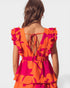 Woman wearing an orange and pink floral dress with a open back on a white background